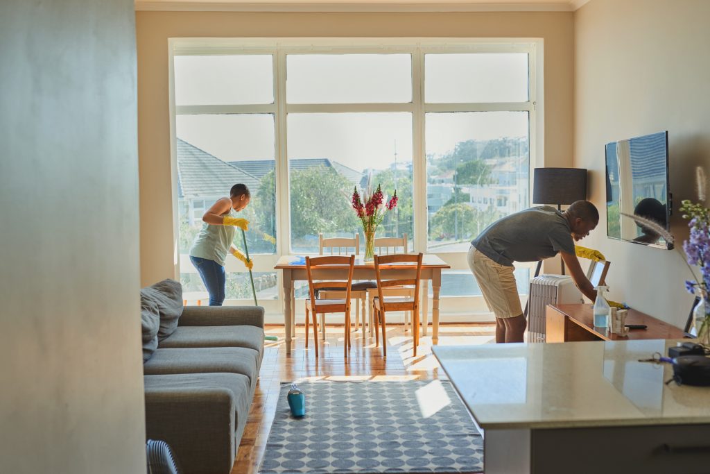 Two people cleaning and decluttering a bright living room to prepare your home for a successful sale